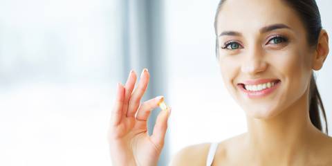 Woman with glowing healthy skin about to take her fish oil supplement
