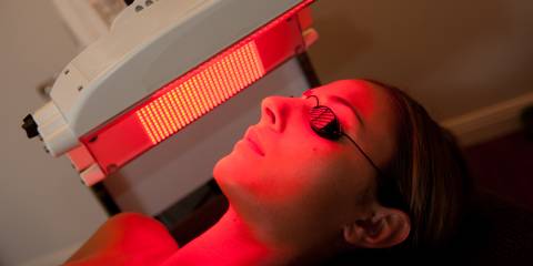 a woman having red light therapy applied to her face
