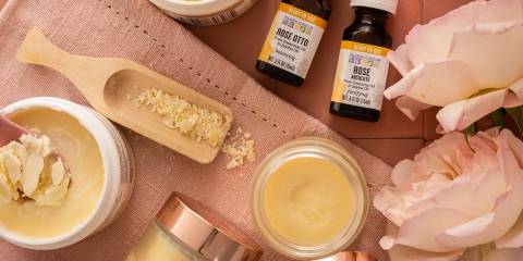 a tub of cocoa butter and bottles of rose essential oils