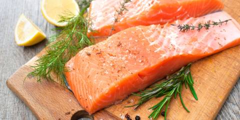 salmon on a cutting board with rosemary and lemon