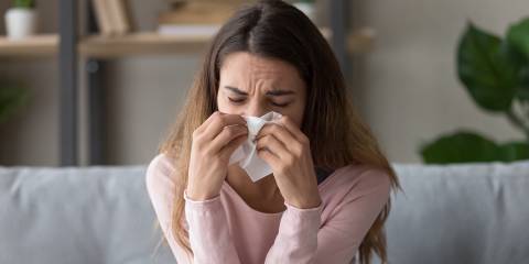 a sick woman sneezing into a tissue