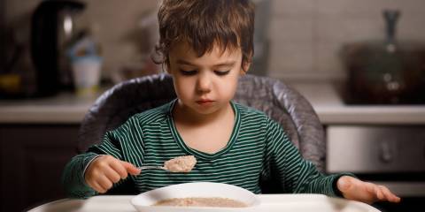 a young boy on the spectrum, looking concerned about his porridge