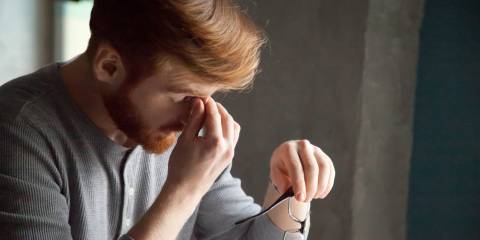 Tired red haired man massaging nose feeling fatigue from work.