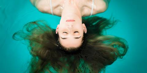 A woman floating in the water of a flotation tank in a relaxed state.