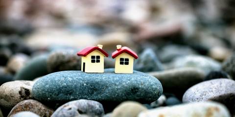 two small model houses sharing a pebble by the sea