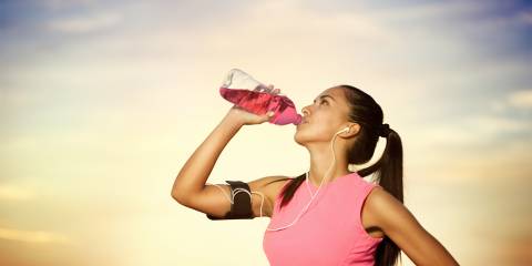 an athletic woman drinking a cherry-flavored supplement drink