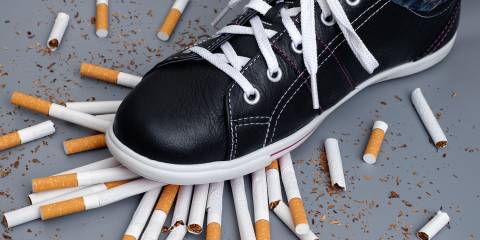 a man stomping on a pile of broken cigarettes