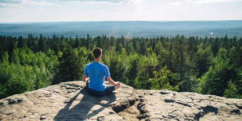 a man meditating on a mountain top with a beautiful view