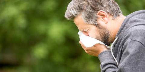a middle-aged man sneezing into a tissue