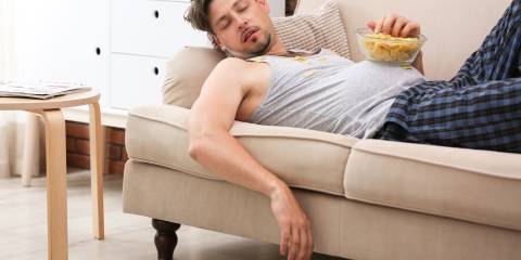 a man that fell asleep on the couch eating junk food