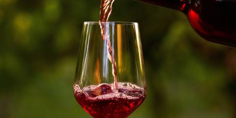 Red wine being poured from a bottle into a wine glass.