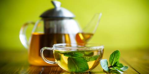 a kettle and cup of loose-leaf green tea
