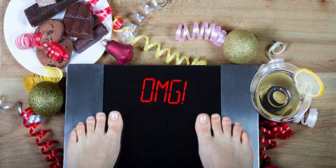 A woman weighting herself after the holidays. The scale says "OMG!"