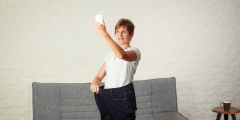 A middle-aged woman taking a selfie in pants that are too big now