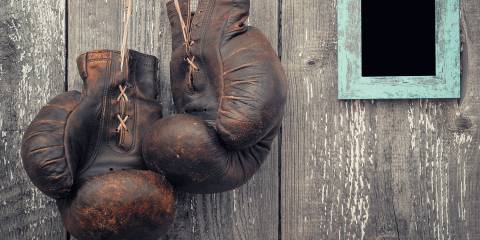 A pair of leather boxing gloves hanging on a barn wall.