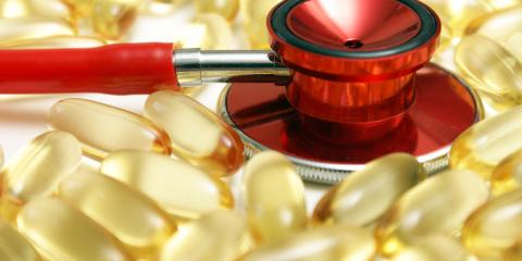 Red stethoscope resting on omega 3 capsules.