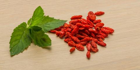 Bright red berberine next to a green leaf. 