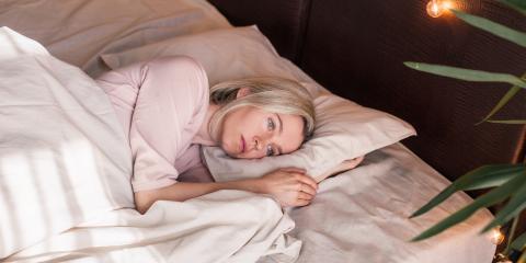 A blonde woman in early middle-age lying awake at night. 