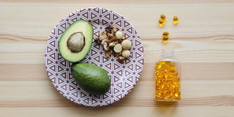 Plate with a halved avocado on it, nuts, and fish oil supplements to the side of plate.