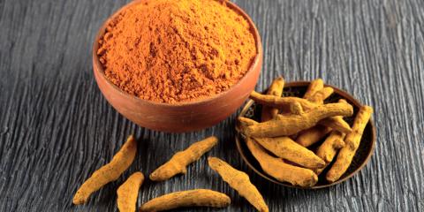 A bowl of orange turmeric with ginger around it.