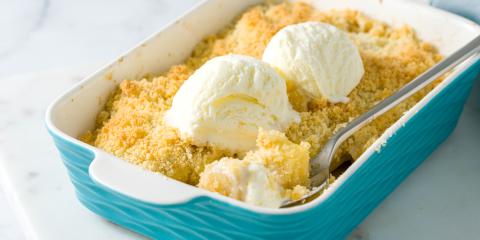 Aqua baking pan filled with fruit crumble with two small scoops of ice cream on top.