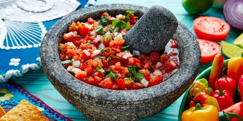 a stone mortar and pestle filled with salsa fresca