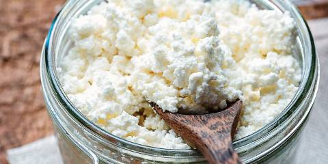 Homemade ricotta cheese is a jar with a wooden spoon.
