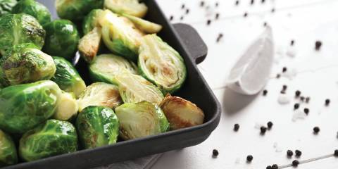 Roasted Brussels Sprouts in a black baking dish on a white table.
