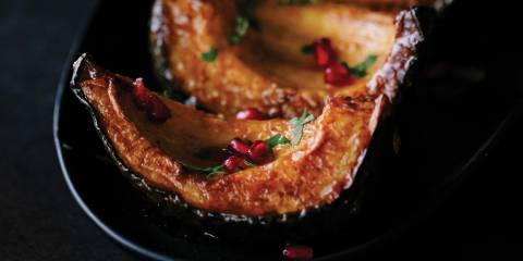 Spice-Drizzled Acorn Squash served on a black platter with a black background.