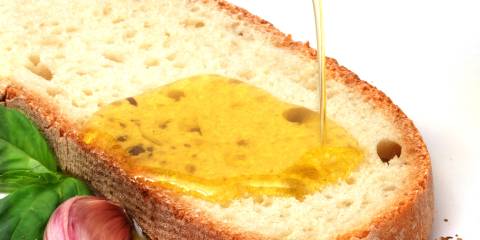 garlic cloves and oil being poured onto bread