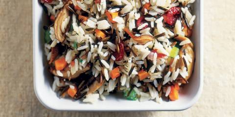 Wild Rice and Mushroom Stuffing in a white serving dish on a tan background.