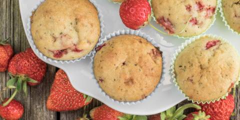 Top view on a strawberry muffins on white plate on a old wooden board