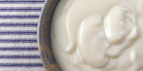 A top view of a bowl of vanilla yogurt with a blue and white striped background.