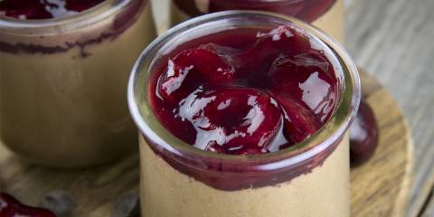 serving jars filled with chocolate mousse with cherries on top