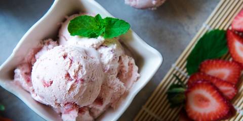 Homemade strawberry ice cream with fresh strawberries in a bowl.