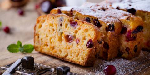 Homemade Pumpkin Cranberry Bread on a cutting board dusted with powdered sugar.