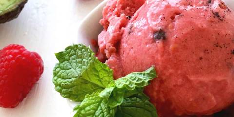 a dish of sorbet next to fresh avocado and raspberries