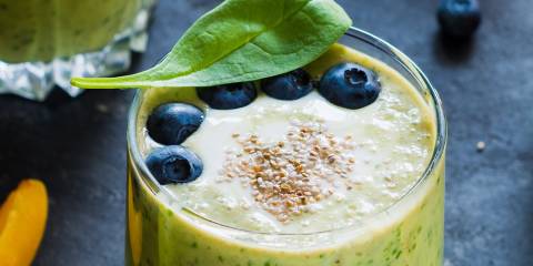 a smoothie made with bananas, blueberries, seeds, and spinach