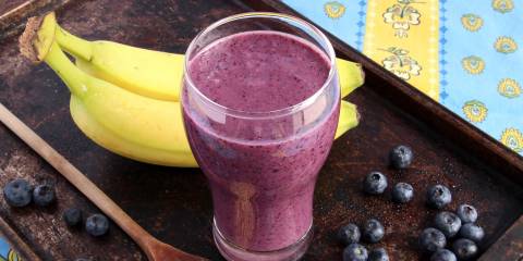Blueberries and bananas next to a glass of berry smoothie with chia seeds