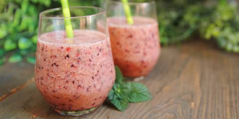 Two watermelon raspberry smoothies on wooden table.