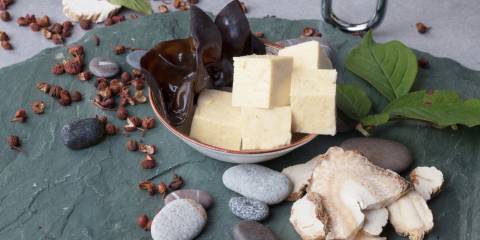 Shiitake mushrooms, tofu and basil ingredients for recipe on a stone slab.