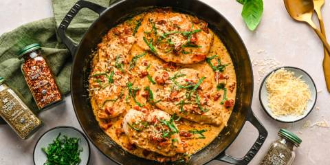 a skillet of chicken and sauce with herbs