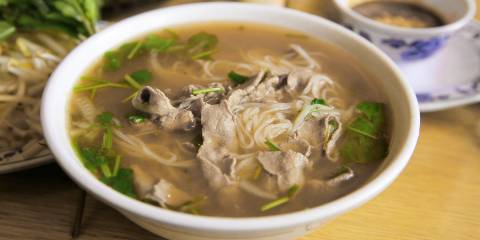 a bowl of soup with monkfish, noodles, and greens