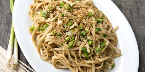 a plate of stir-fried udon noodles with green onions
