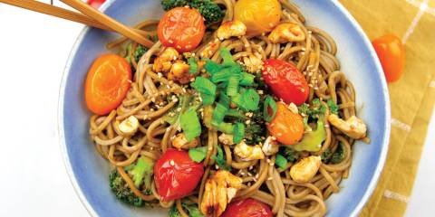 a bowl of noodles with cherry tomatoes and candied cashews