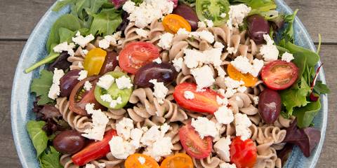 A bowl of pasta salad topped with vegan tofu feta