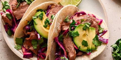 a plate of beefy steak tacos with slaw and avocado