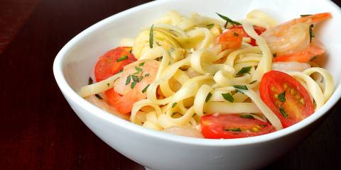 Summer Shrimp Linguine with Tomatoes & Artichokes served in a white bowl.
