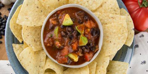 a bowl of chunky salsa surrounded by tortilla chips