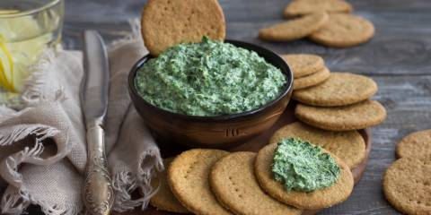 Vegan green spinach dip with on a wooden board with oat crackers,